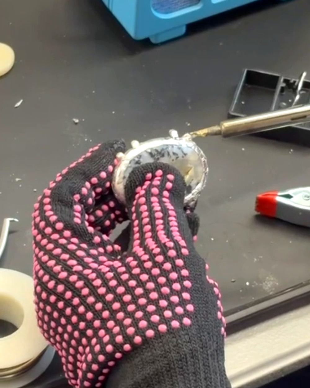 A student soldering a stone pendant with a heat resistant glove at a Hermara Creatives jewelry workshop in Cleveland Heights