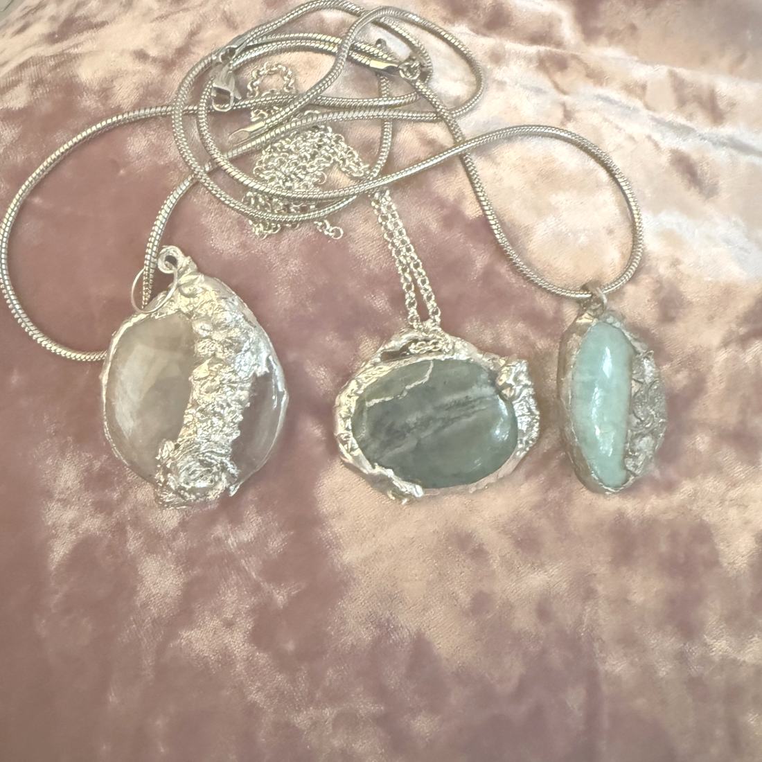 Three handmade stone pendants in hand soldered silver settings on blush velvet by Hermara Creatives